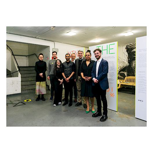 Group photo on which eight people are depicted. They are standing in the hallway in front of the exhibition.