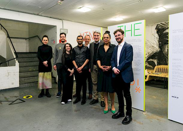 Group photo on which eight people are depicted. They are standing in the hallway in front of the exhibition.