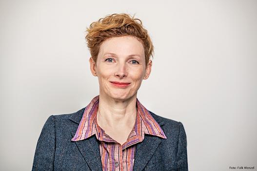 Zu sehen ist ein Portraitfoto von Katarzyna Wielga-Skolimowska, Künstlerische Direktorin der Kulturstiftung des Bundes. Sie lächelt mit geschlossenem Mund.